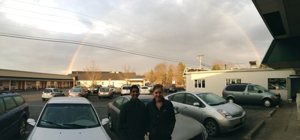 Jenna and Varun standing in front of a double rainbow